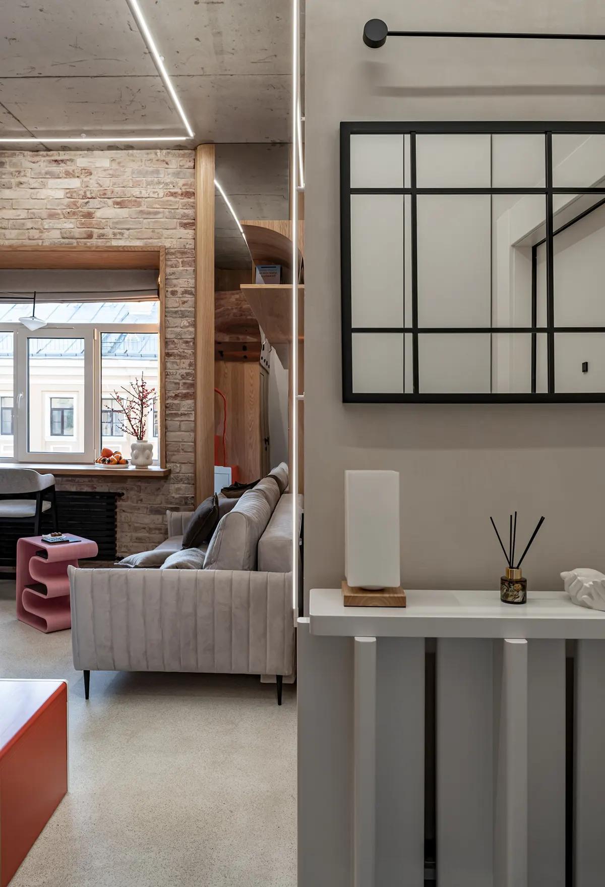 Входная зона с зеркалом в черную сетку, настольной лампой в минималистичном интерьере квартиры в историческом центре Кронштадта