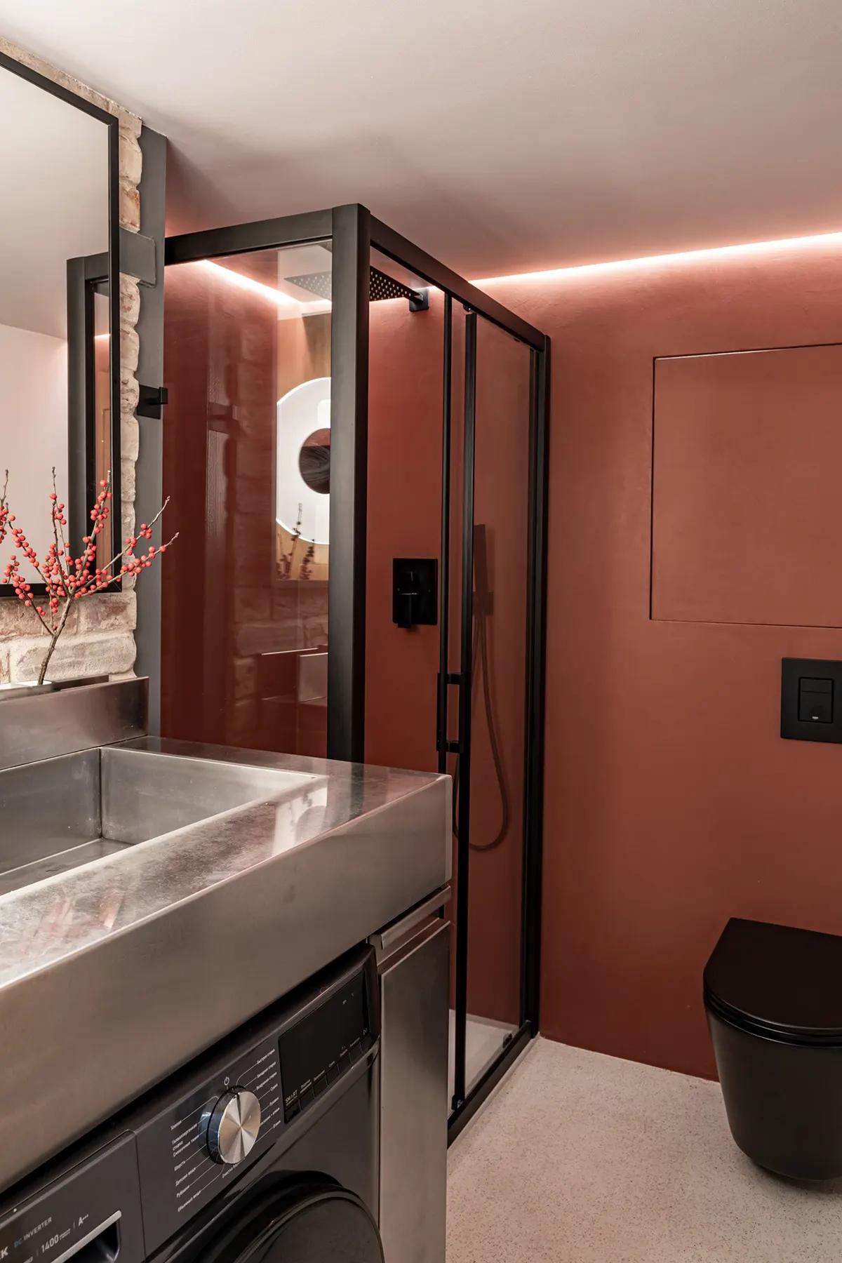 Современная ванная комната с красными стенами и душем за стеклянной перегородкой