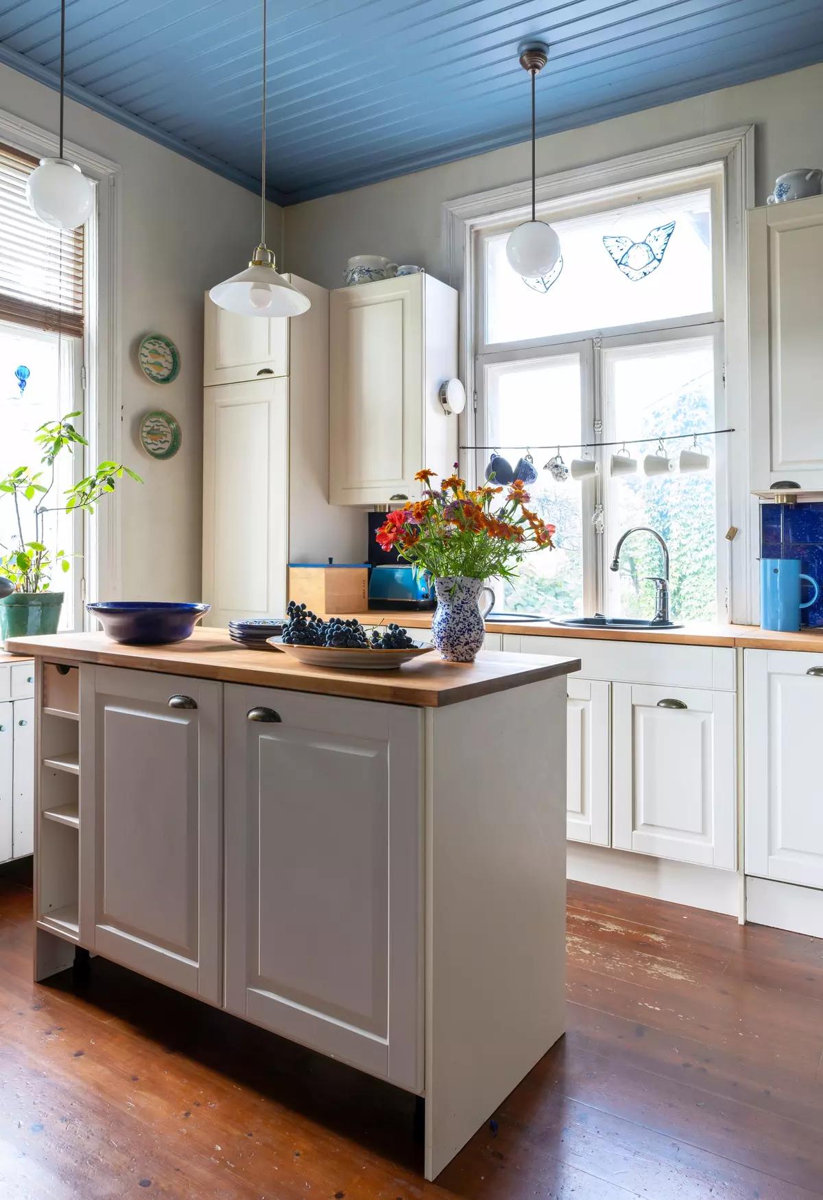 Небольшой кухонный остров с деревянной столешницей в белой кухне