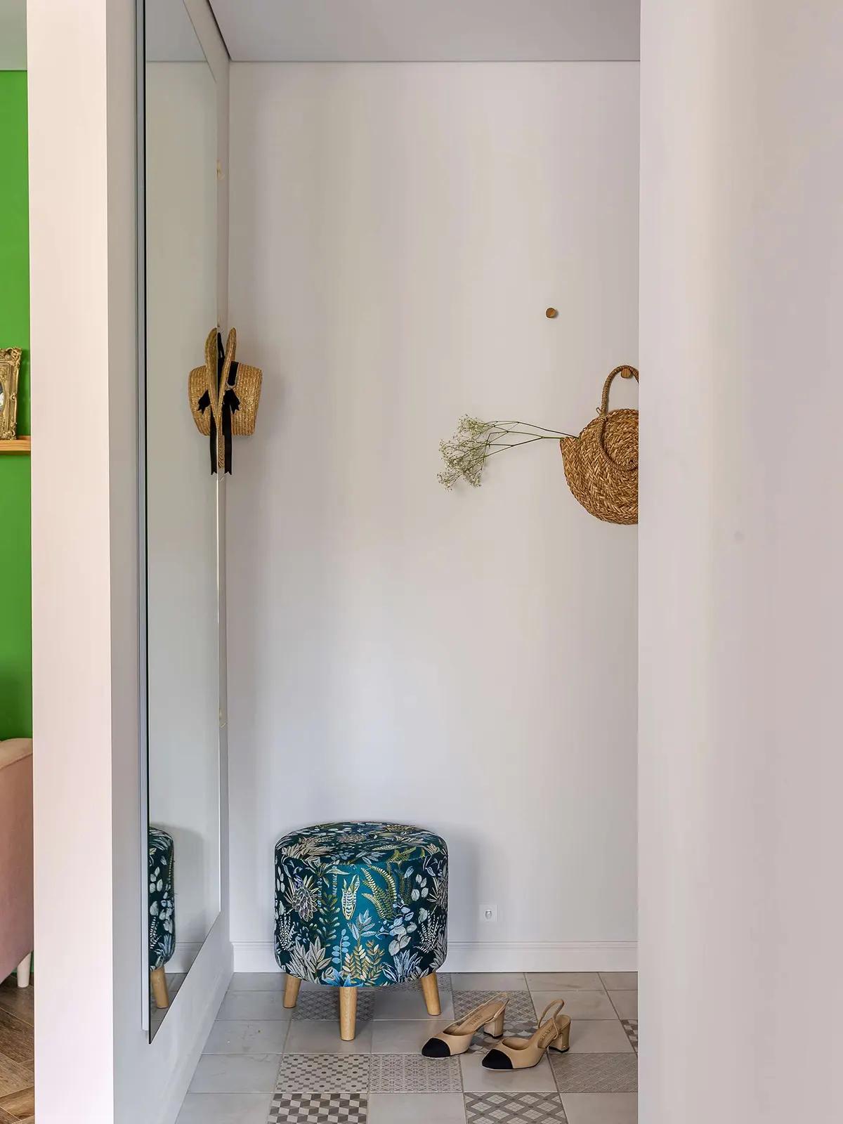 Уютная прихожая в хрущевке с зеркалом, соломенной шляпой на крючке, сушеными цветами, цветным пуфиком и бежевыми туфлями на плиточном полу