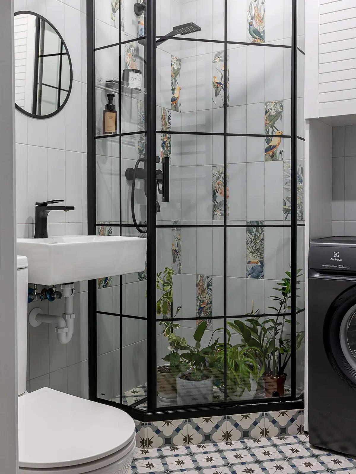 Ванная комната с тропической плиткой с птицами и растениями, черной душевой кабинкой, живыми растениями внутри, стиральной машиной, белой раковиной и узорным полом