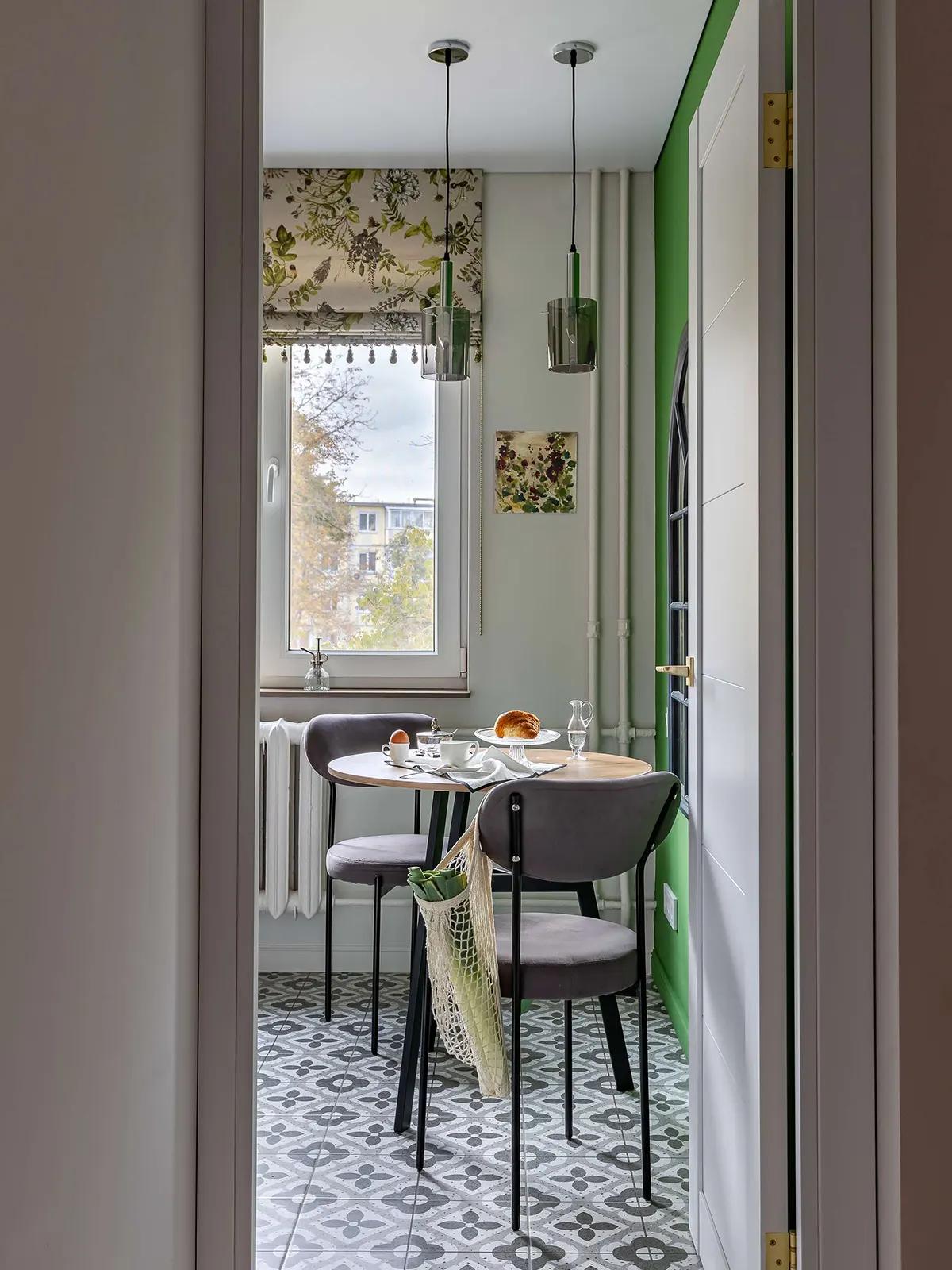 Вид на компактную кухню через дверной проем с круглым столом и серыми стульями