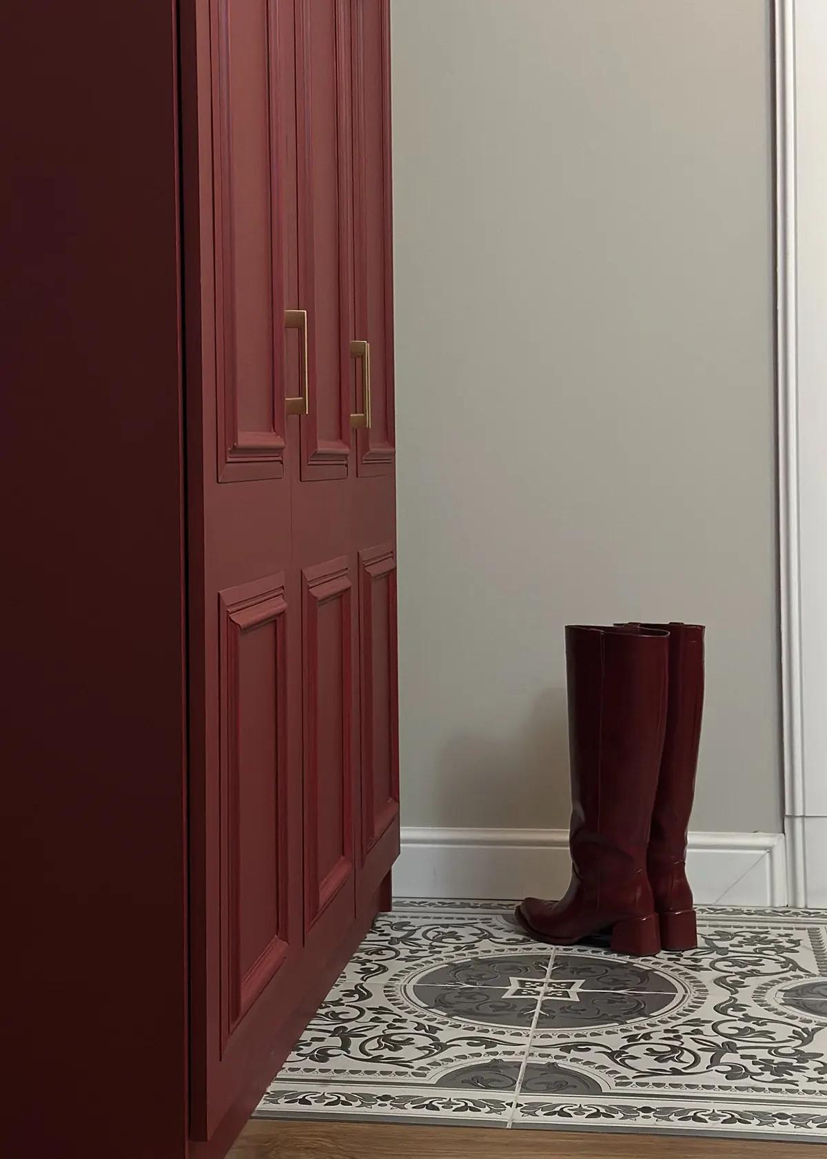 Готовый реставрированный шкаф в бордово-красном цвете с золотыми ручками рядом с темно-бордовыми сапогами