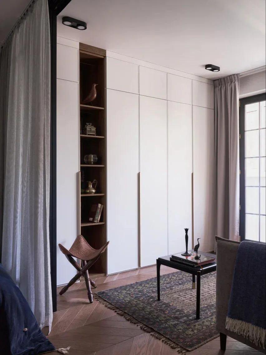Белые шкафы под потолок в гостиной, журнальный столик, ковер на полу