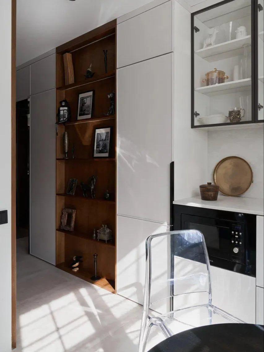 Вид из кухни на высокий деревянный стеллаж