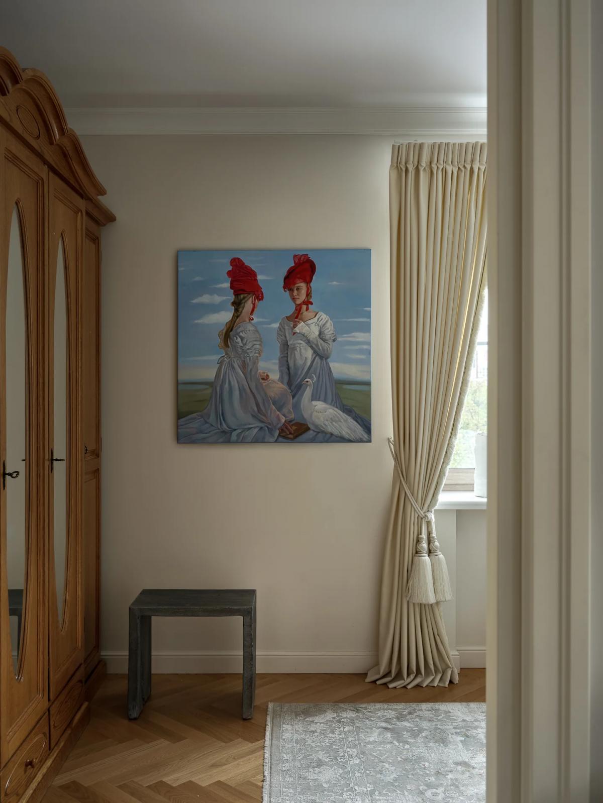 Картина с женщинами в белых платьях и красных шляпах в спальне на бежевой стене